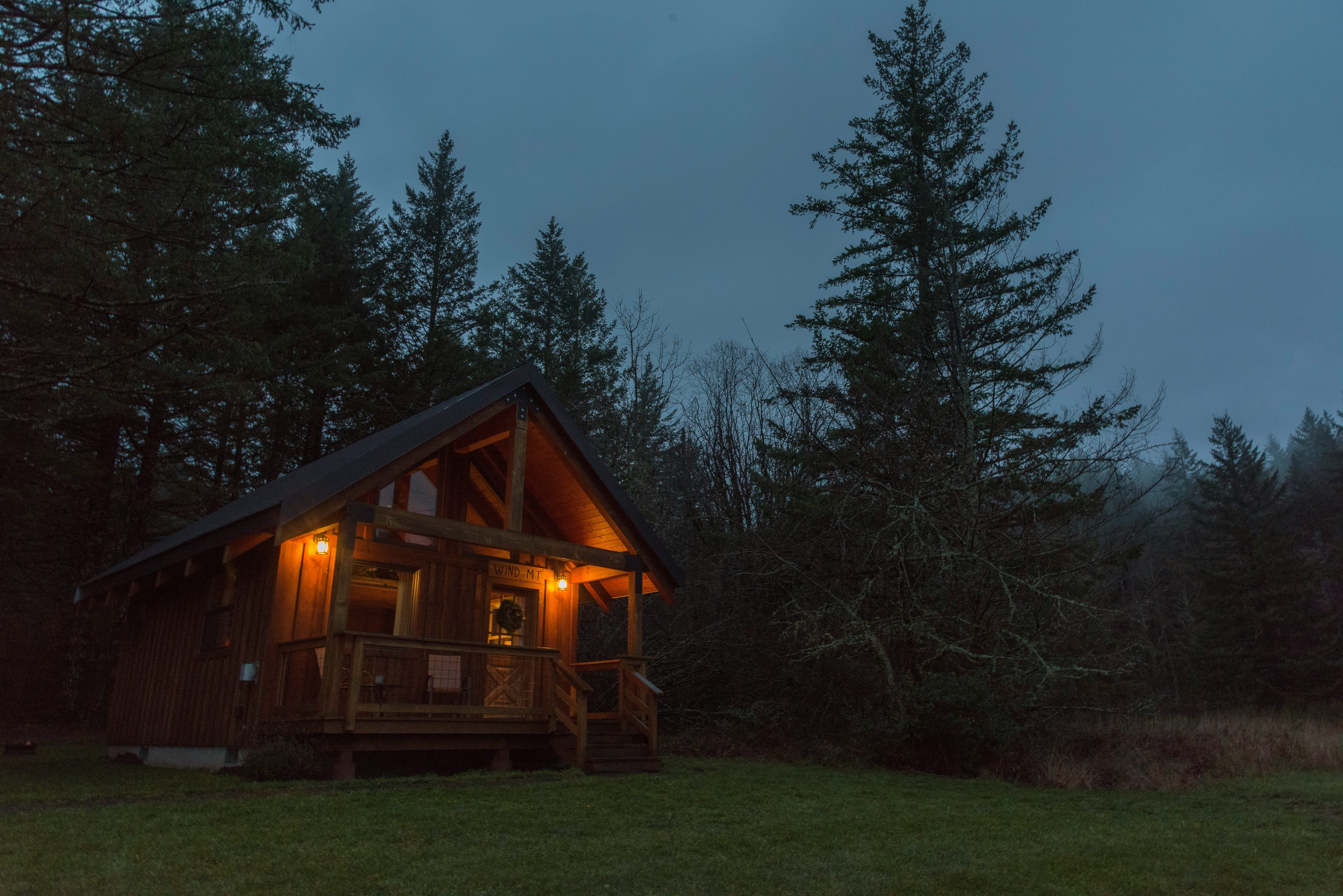 Cabin between trees with lights on